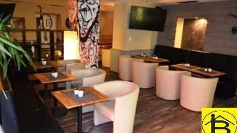 Gemütlicher Barbereich mit bequemen Sitzgelegenheiten, Holztischen und moderner Wanddekoration.
