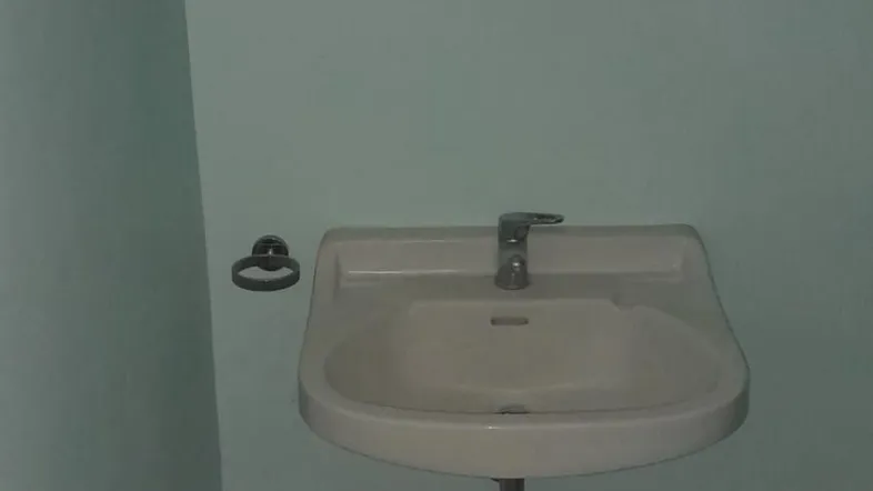 Kleines Gäste-WC mit Waschbecken und Spiegel, in einem schlichten Design gehalten.