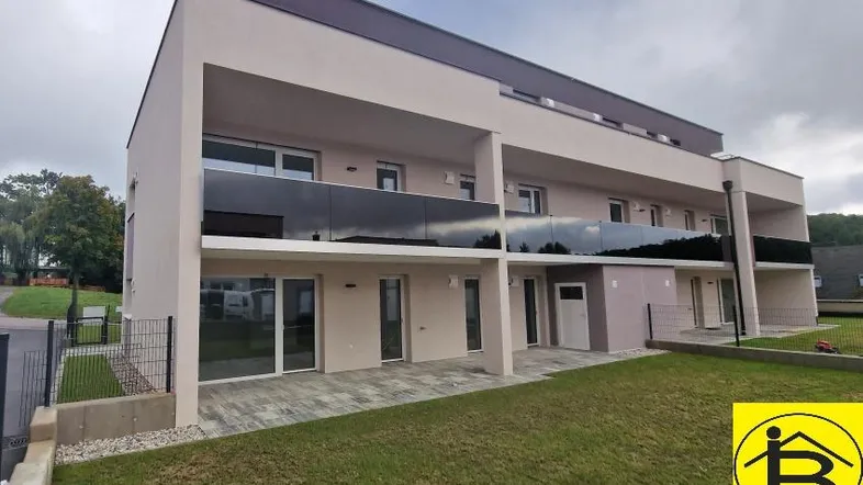 Moderne Wohnanlage mit mehreren Wohneinheiten, Balkonen und privaten Gärten.