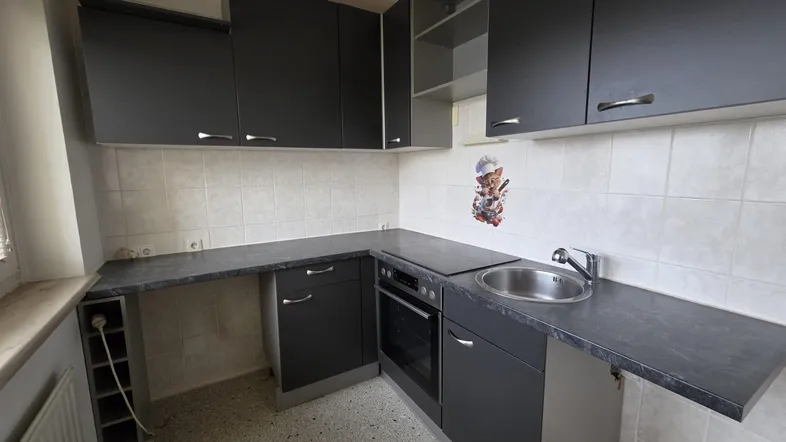 Funktionale Küche mit dunklen Schränken, heller Fliesenrückwand und integrierten Geräten.
