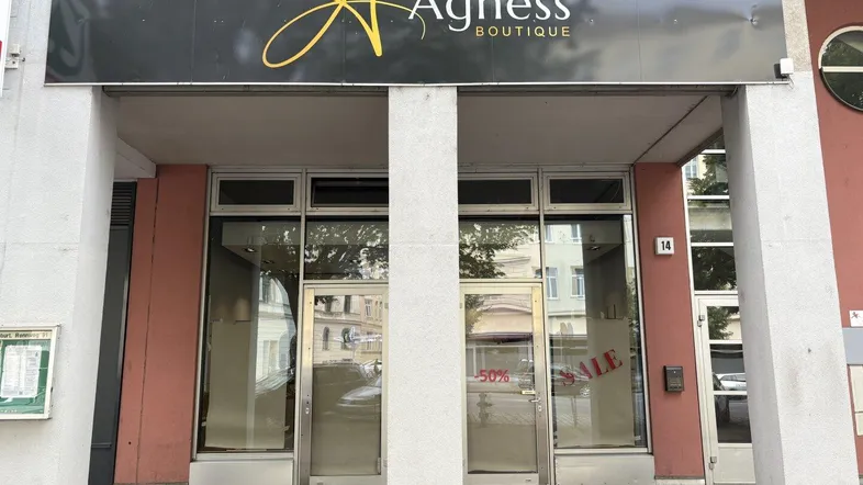 Eingangsbereich einer Boutique mit großen Schaufenstern und einem prominenten Firmenschild.