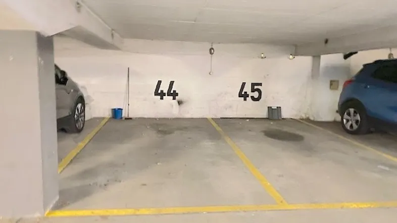 Tiefgaragenstellplätze mit Markierungen und parkenden Fahrzeugen in einer hellen Umgebung.