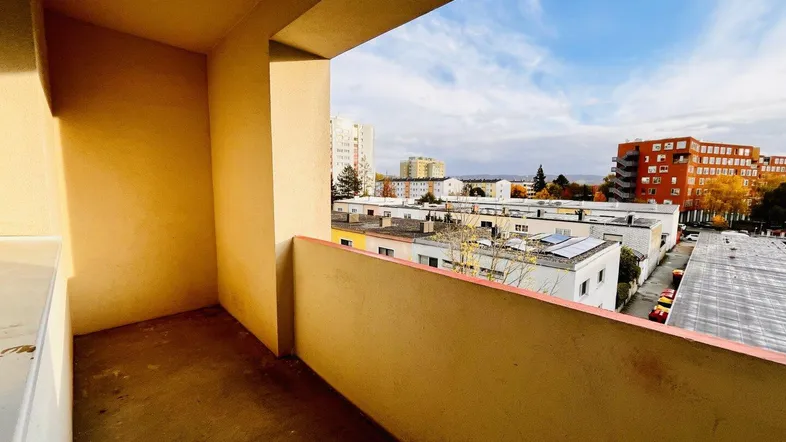 Geräumiger Balkon mit Blick auf die umliegenden Gebäude und den Himmel.