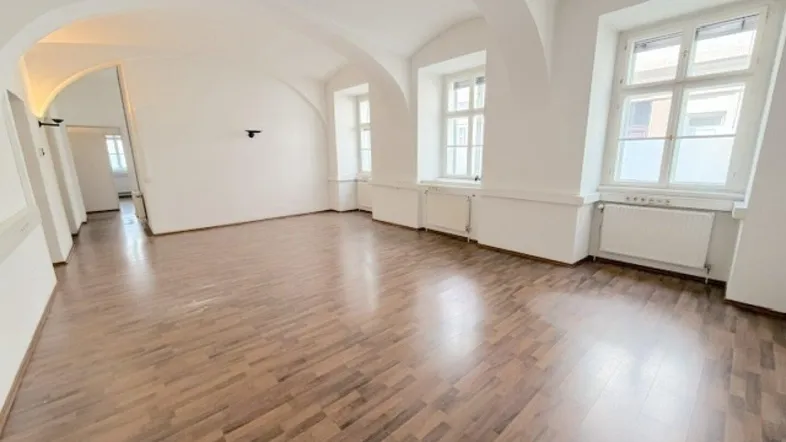 Helles, leeres Zimmer mit Holzboden und gewölbter Decke, bereit zur individuellen Gestaltung.