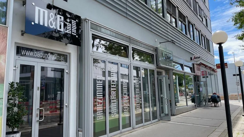 Moderne Geschäftsfassade mit großen Fenstern und einem Bad- und Raumdesign-Geschäft im Erdgeschoss.
