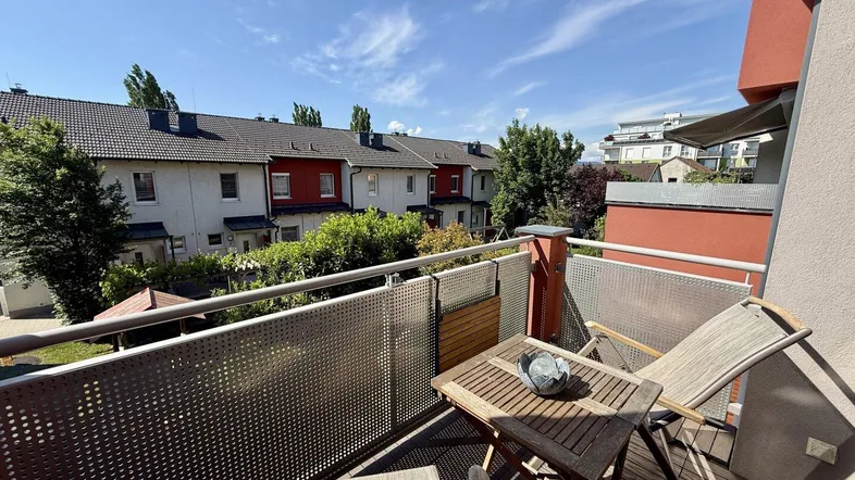 Heller Balkon mit Holzboden und Sitzgelegenheiten, bietet einen schönen Blick auf die Nachbarschaft.