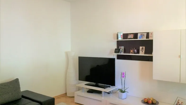 Helles Wohnzimmer mit modernem Medienmöbel, bequemer Couch und hellem Parkettboden.