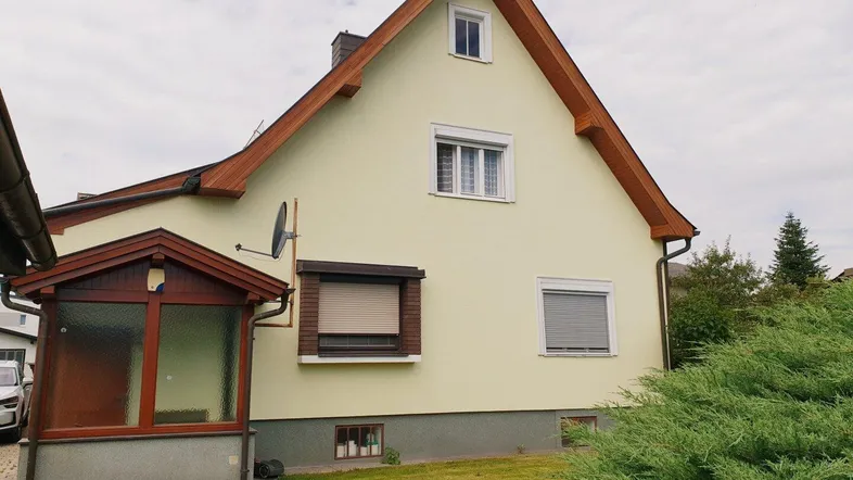 Seitenansicht des Hauses mit gepflegtem Rasen und einem Wintergartenanbau.