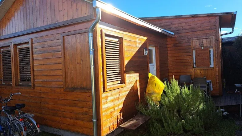 Hölzernes Ferienhaus mit Fensterläden und Fahrrädern im Vorgarten unter blauem Himmel.