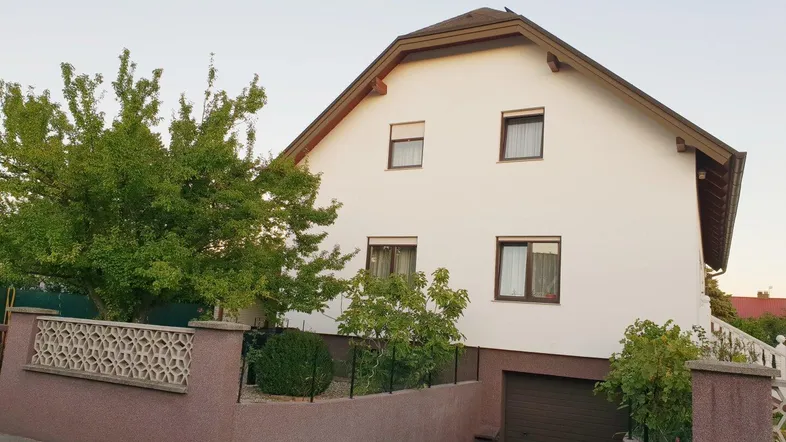 Rückansicht des Hauses mit integrierter Garage und einem gepflegten Vorgartenbereich.