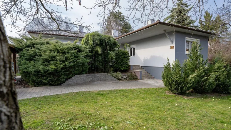 Einfamilienhaus mit Vorgarten und gepflastertem Zugangsbereich unter klarem Himmel.