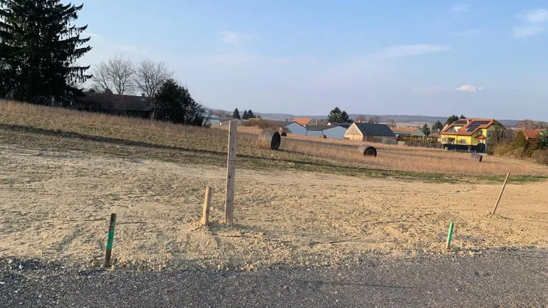 Leeres Grundstück mit Schotterweg und Blick auf die umliegende Landschaft und Häuser.
