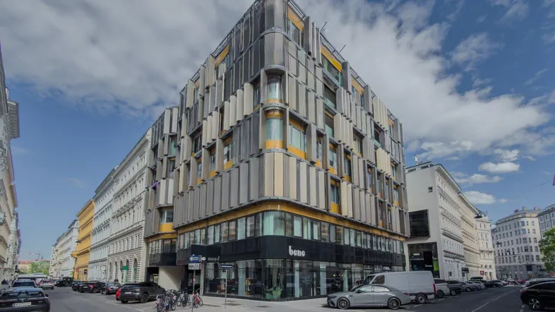 Modernes Eckgebäude mit markanter Fassadengestaltung und großen Fenstern in urbaner Umgebung.