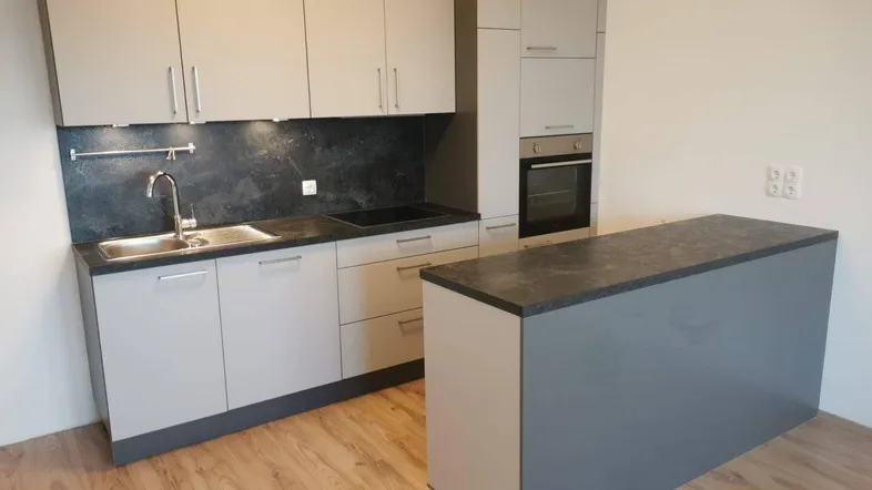 Moderne Einbauküche in Grau mit Kücheninsel und integrierten Geräten, ideal für offenes Wohnen.
