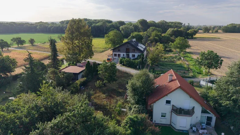 Drohnenaufnahme von mehreren Häusern mit Gärten und angrenzenden Feldern in ländlicher Umgebung.