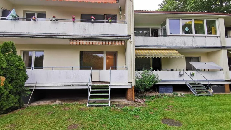 Mehrfamilienhaus mit mehreren Balkonen und Zugang zum Gemeinschaftsgarten.