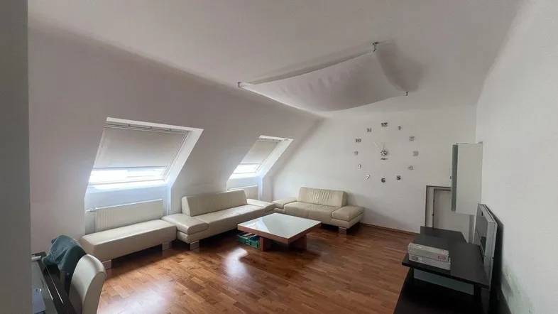 Helles Wohnzimmer im Dachgeschoss mit Holzboden, gemütlichen Sofas und zwei Dachfenstern.