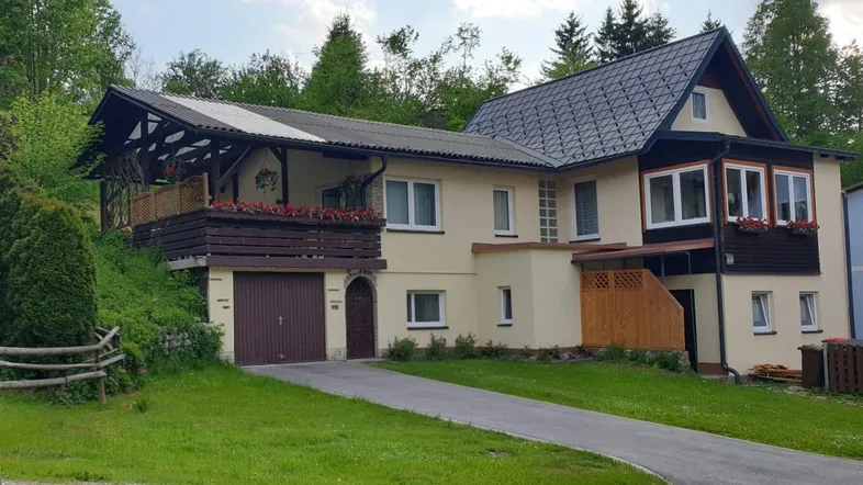 Einfamilienhaus mit Garage, Balkon und Garten in ländlicher Umgebung.