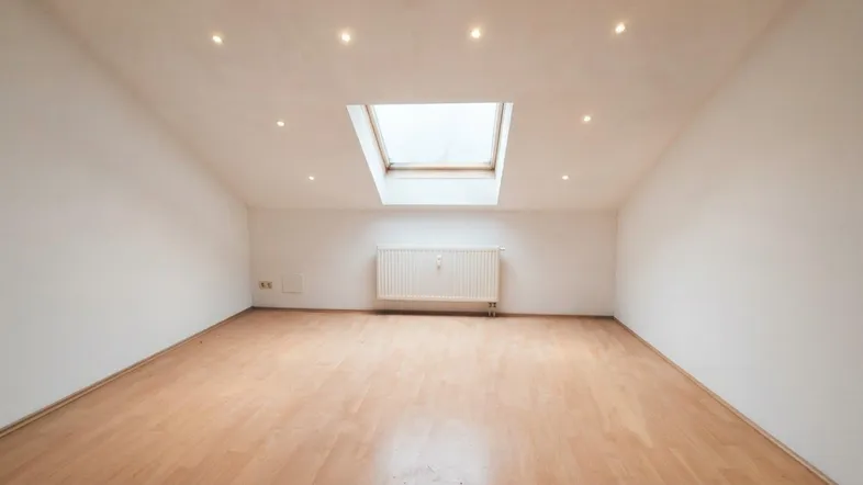Heller Raum mit Dachfenster, Einbaustrahlern und Laminatboden, ideal für Wohn- oder Schlafzimmer.