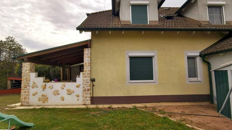 Überdachte Terrasse mit Steinmauer und Blick auf den Gartenbereich des Hauses.