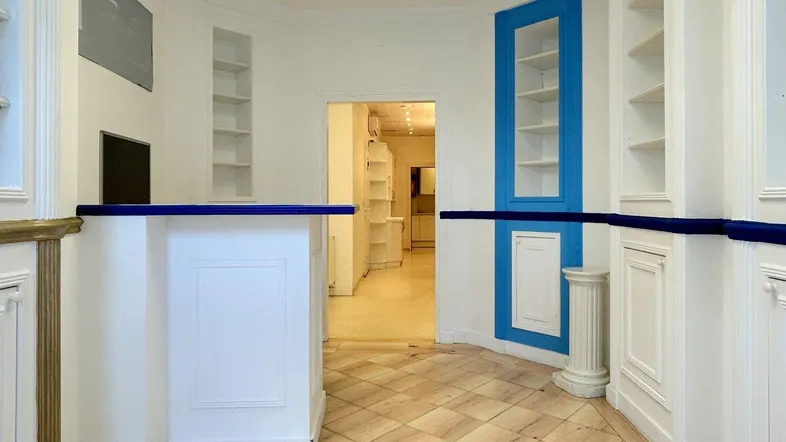 Heller Geschäftsraum mit Empfangstheke, eingebauten Regalen und blauen Akzenten, ideal für Einzelhandel oder Büro.