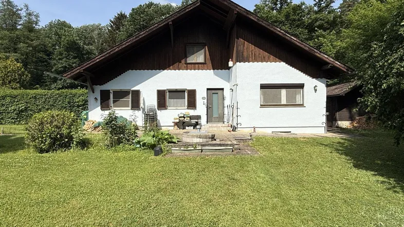 Traditionelles Einfamilienhaus mit weißer Fassade, Holzelementen und großem Gartenbereich.