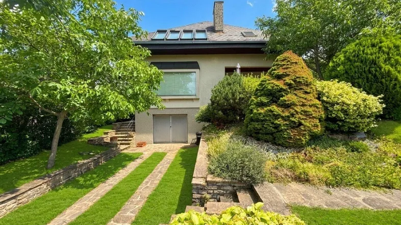Vorderansicht des Hauses mit gepflegtem Garten, Auffahrt und integrierter Garage.
