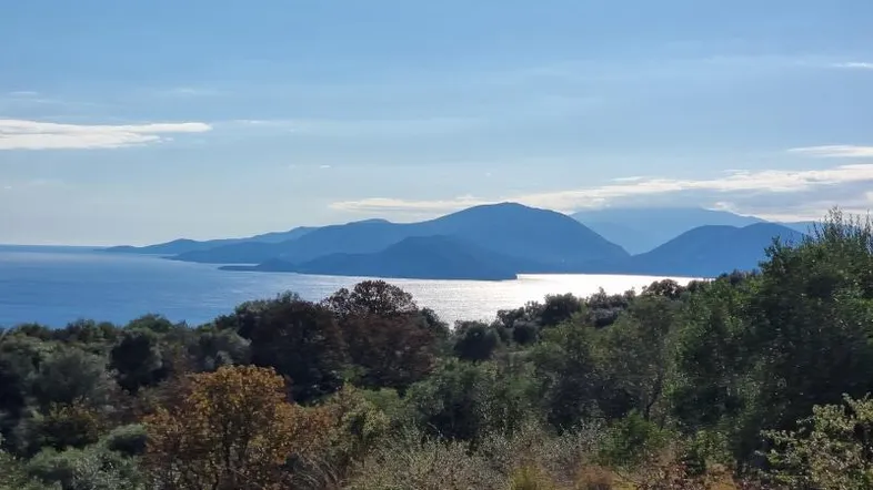 Panoramablick auf das Meer und die umliegenden Berge unter einem klaren blauen Himmel.