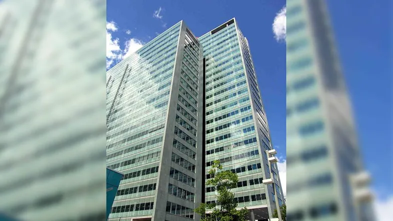 Modernes Hochhaus mit Glasfassade unter blauem Himmel und Wolken, das eine zeitgenössische Architektur zeigt.