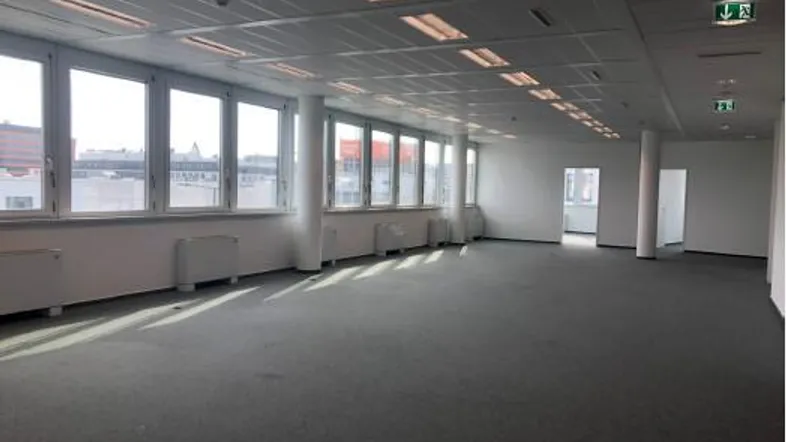 Großes, helles Büro mit Teppichboden, vielen Fenstern und weitem Blick auf die Stadt.