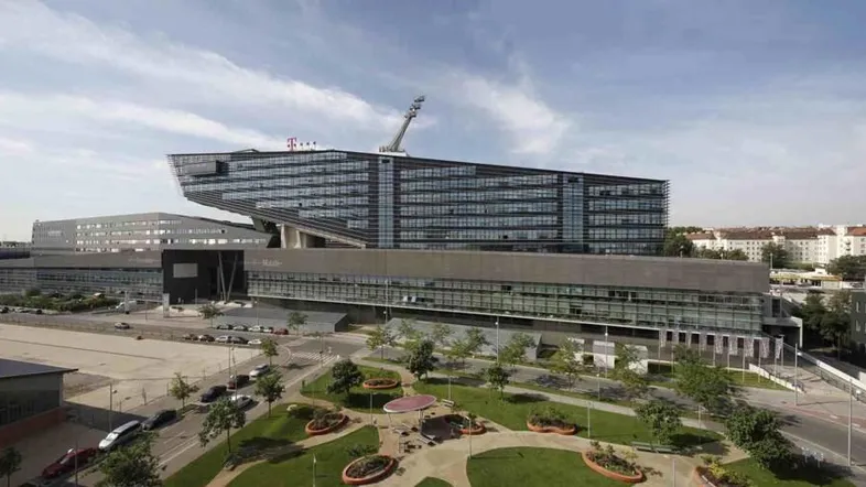Panoramablick auf ein großes, modernes Bürogebäude mit markanter Architektur und umliegender Grünfläche.