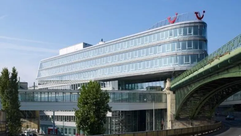 Modernes Bürogebäude mit geschwungener Glasfassade und angrenzender Brücke unter klarem Himmel.