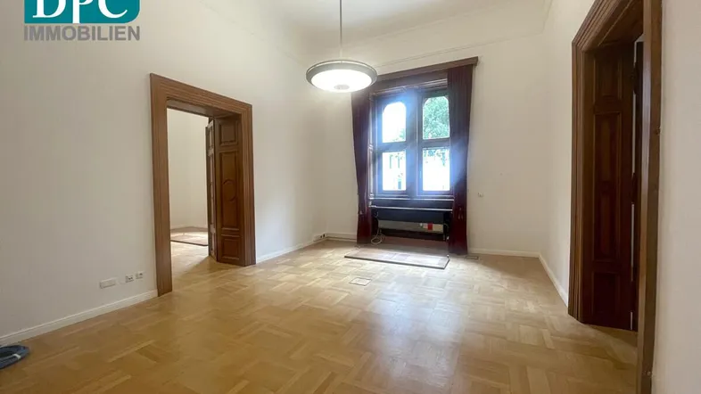 Geräumiger Raum mit Fischgrätparkett, hohen Decken und großen Holzfenstern, ideal als Büro oder Wohnzimmer.