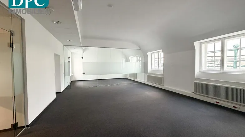 Geräumiges Büro mit Teppichboden, großen Fenstern und moderner Glasabtrennung, das viel Tageslicht hereinlässt.
