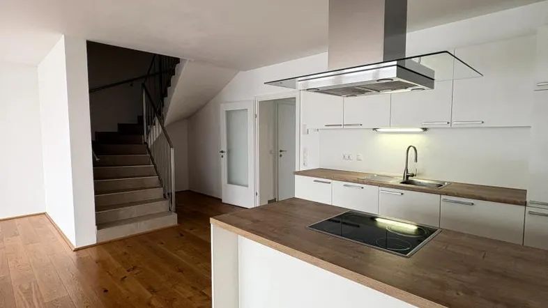 Moderne offene Küche mit Kochinsel, Holzarbeitsplatte und Zugang zur Treppe.