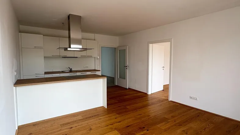 Heller offener Wohn-Essbereich mit moderner Einbauküche und Holzboden.