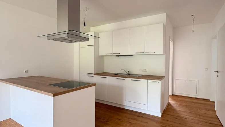 Moderne Einbauküche mit weißen Fronten, Holz-Arbeitsplatte und Kochinsel mit Induktionskochfeld.
