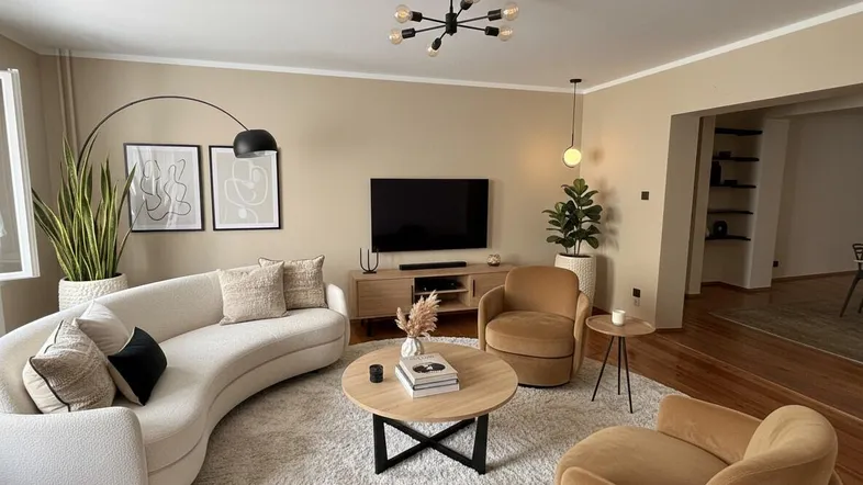 Gemütliches Wohnzimmer mit beigem Farbschema, modernem Sofa und stilvoller Beleuchtung.