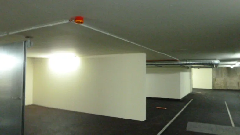 Geräumiger Kellerraum mit Betonboden und sichtbaren Installationen, ideal als Lagerfläche oder Tiefgarage.