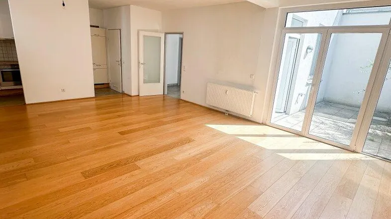 Helles Wohnzimmer mit Holzboden und Zugang zu einer Terrasse, ideal für entspannte Stunden.