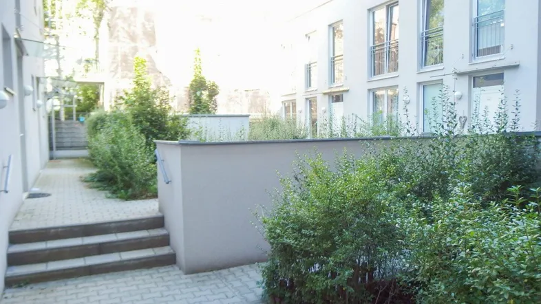 Blick auf den gepflasterten Innenhof mit Grünflächen und modernen Gebäudefassaden.