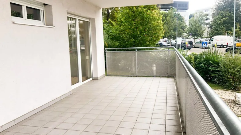 Geräumiger Balkon mit Fliesenboden und Metallgeländer, bietet Blick auf die Umgebung.