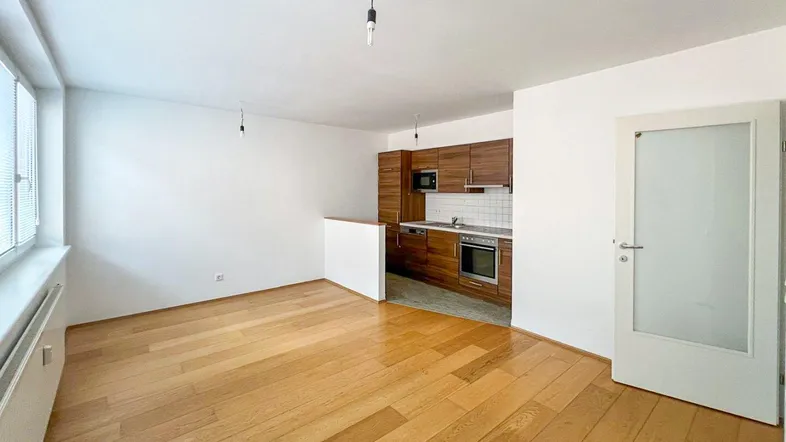 Heller Wohnbereich mit Holzboden und integrierter Küchenzeile, ideal für offenes Wohnen.