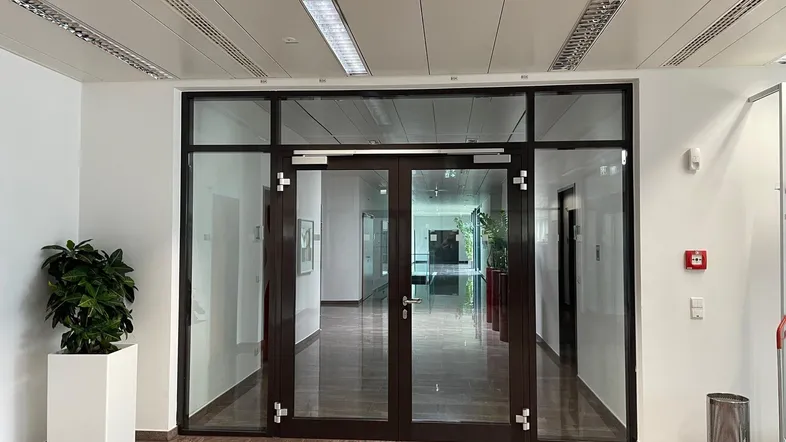 Geräumiger Eingangsbereich mit glänzenden Marmorböden und Glastüren, der zu weiteren Büroräumen führt.