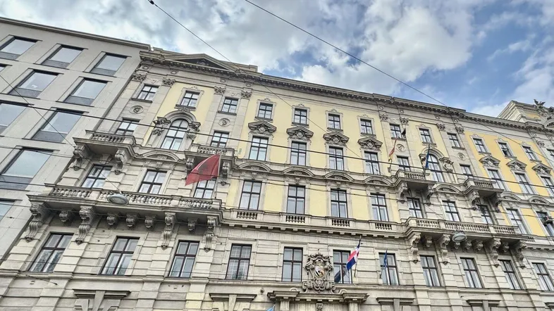 Historisches Gebäude mit klassischer Fassade, Balkonen und dekorativen Elementen unter bewölktem Himmel.