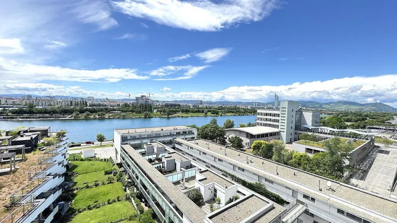 Panoramablick über die Stadt, den Fluss und moderne Wohngebäude unter blauem Himmel.
