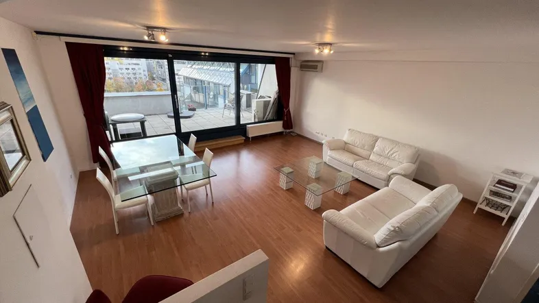 Helles Wohn- und Esszimmer mit Parkettboden, weißen Sofas und Zugang zur Terrasse.