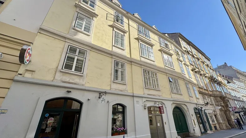 Historisches Gebäude mit gelber Fassade und traditionellen Fenstern in einer Stadtstraße.