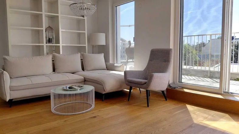 Helles Wohnzimmer mit modernem Design, Holzboden, Klimaanlage und Zugang zu einem Außenbereich.