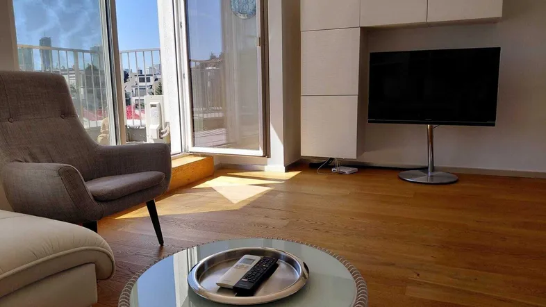 Helles Wohnzimmer mit Holzboden, modernen Möbeln und Zugang zu einem sonnigen Balkon.